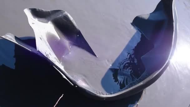 오래된 자동차의 찢어진 날개는 일광에 도로에 웅덩이에 떠아스팔트의 부재물 웅덩이에 — 비디오