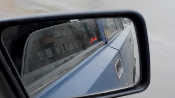 透过复古汽车的脏镜 一条房子的道路和一辆开着小灯的车在后面行驶 右侧脏车后视镜 后视镜 — 图库视频影像