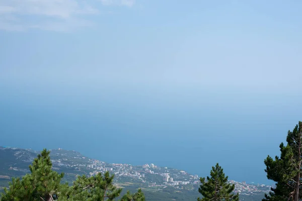 The sea and the city from the mountains from the bird\'s eye view of the beautiful blue sea of water reflecting the clouds on the background of green mountains and South of the city Sea city on the background of greenery and the sea in the afternoon o