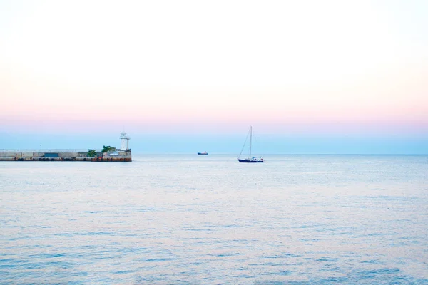 Deniz günbatımı, deniz feneri yakınında denizde yatlar bir yaz günü gökyüzü deniz günbatımı güzel renklerin arka planda doğal ışık ile akşam yaz aylarında gün batımı 
