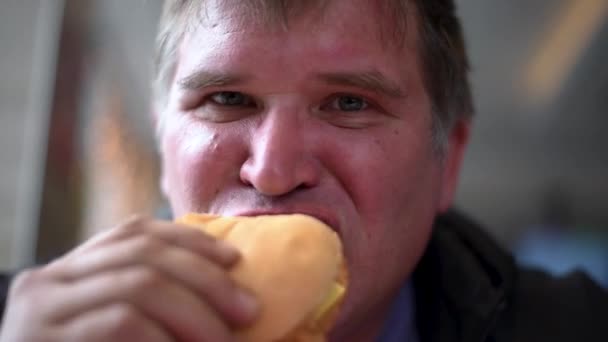 空腹の男は 大きな飲み物を一口食べて チューブマンがサンドイッチを食べて ガラスから飲み物でハンバーガーやホットドッグを食べます — ストック動画