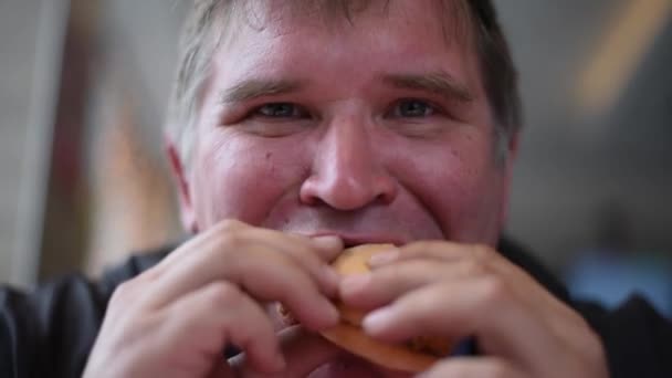 空腹の男は 大きな飲み物を一口食べて チューブマンがサンドイッチを食べて ガラスから飲み物でハンバーガーやホットドッグを食べます — ストック動画