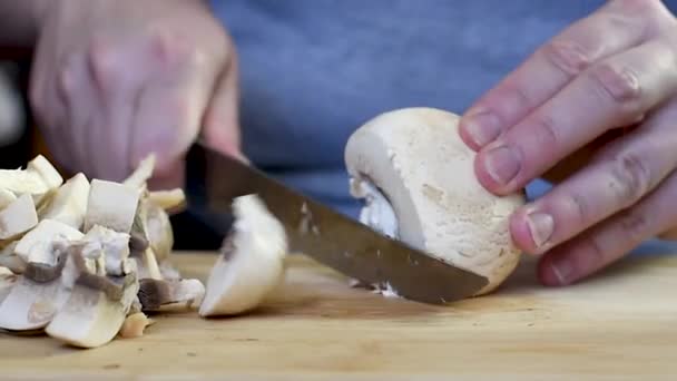 一位妇女在家里用黑柄在厨房里用刀子在木板上切蘑菇 蘑菇切割的特写 在木板上切割蘑菇烹饪 — 图库视频影像