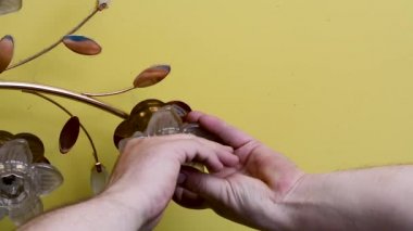 Bir adam özel bir anahtar ile avize tavan ışığı nı söker, sarı streç tavan karşı, yakın çekim gün ışığında sarı bir streç tavan arka plan üzerinde avize anahtarı kaldırma