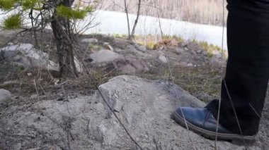 Ormanda off-road yapan bir kadın, taşlarda tökezler, baharda mavi ayakkabılarla, yakın plan. Çizmeli kadınların ayakları ormandan geçer.  
