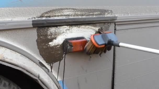 旅行后用特殊的刷子和水清洗公共汽车 一个男人在露天里把一辆肮脏的公共汽车开到一辆公共汽车上 — 图库视频影像