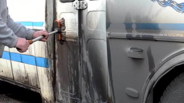 旅行后用特殊的刷子和水清洗公共汽车 一个男人在露天里把一辆肮脏的公共汽车开到一辆公共汽车上 — 图库视频影像