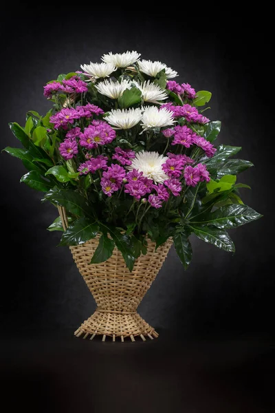 The flower arrangement of the flowers in the basket is used for funerals and bookmarks. Mourning card with a place for inscription. Ritual funeral basket with flowers on a black background