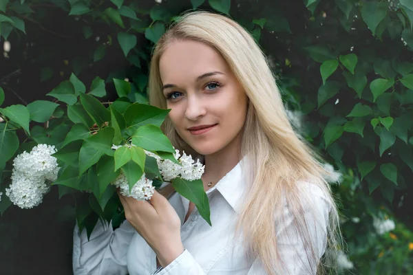 Yeşil yaprakların bir arka plan üzerinde beyaz leylak ile bir kız portresi . Beyaz leylak ve yeşil yaprakları ile kız , bir kız portresi