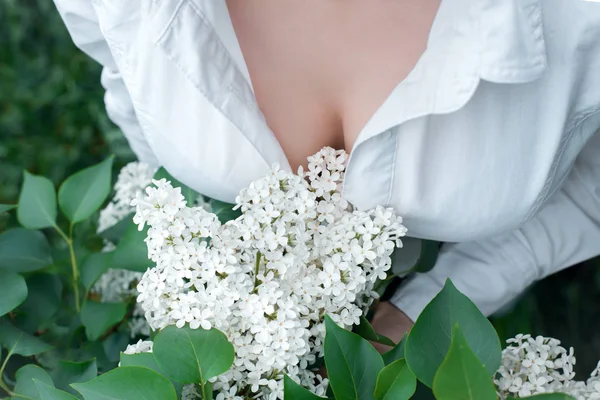 Beyaz leylak ile beyaz bluz Hassas kadın Göğüsler, üst görünümü . Yeşil bir arka plan üzerinde beyaz leylak kadın meme