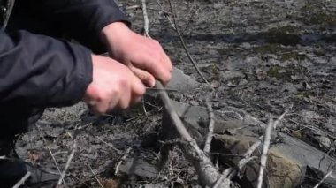 Ormanda hayatta kalmak, odun için kuru dalları testereyle ateş için küçük bir katlanır bıçakla. Adam bahar açık havada bir katlanır bıçak ile bir dalı testere 
