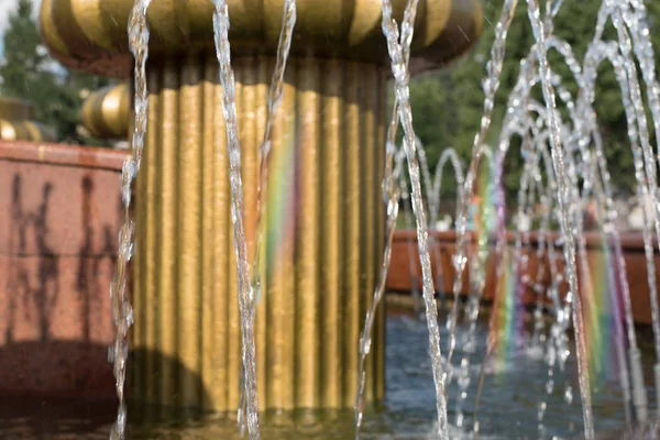 Sıcak bir yaz gününde gökkuşağı ile Şehir çeşmesi. Serin su çeşmesi jetleri Güneşli bir yaz gününde bir gökkuşağı oluşturarak ışık yansıtır