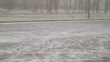 İlkbaharda kar ve rüzgar. Araba kullanırken araba camLarından şehre kar fırtınası. Evlerin arka planda ilkbahar öğleden sonra şehirde kar ve rüzgar 