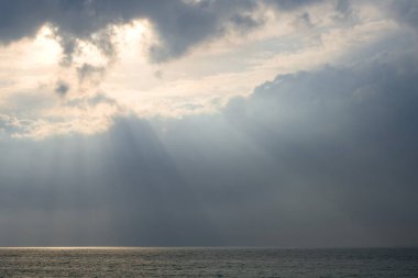 Bulutların arasından gelen güneş ışınlarındaki deniz. Bulutlu bir günde güneş ışığı ışınlarında deniz yüzeyi