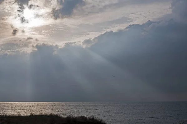 Bulutların arasından gelen güneş ışınlarındaki deniz. Bulutlu bir günde güneş ışığı ışınlarında deniz yüzeyi