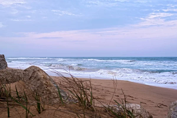 Gün batımında deniz dalgaları ile kumlu plaj. Gün batımında veya gün doğumunda plaj