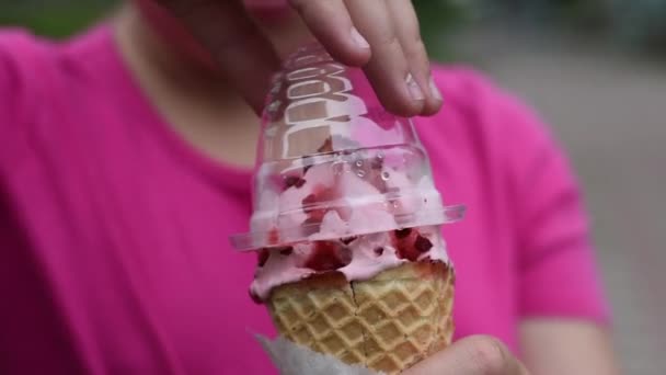 女孩想吃冰淇淋 女孩从草莓冰淇淋中取出包装纸 — 图库视频影像