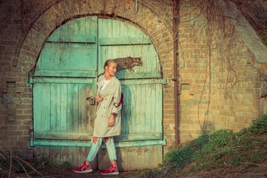 Kedi bir leash üzerinde. Bir kız omuzunda oturur bir kedi ile yürüyor