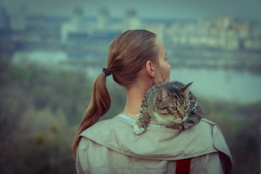 Kedi bir leash üzerinde. Bir kız omuzunda oturur bir kedi ile yürüyor