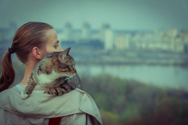 Kedi bir leash üzerinde. Bir kız omuzunda oturur bir kedi ile yürüyor