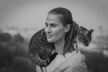 Kedi bir leash üzerinde. Bir kız omuzunda oturur bir kedi ile yürüyor