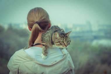 Kedi bir leash üzerinde. Bir kız omuzunda oturur bir kedi ile yürüyor