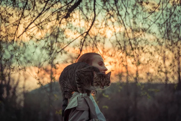 Cat on a leash. A girl is walking with a cat that sits on her shoulder