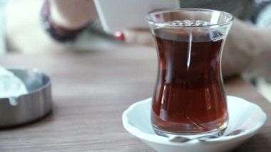 Çay. El bir cep telefonu ile arka plan üzerinde Türk çayı