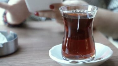 Çay. El bir cep telefonu ile arka plan üzerinde Türk çayı