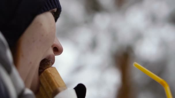 在冬季公园吃香肠卷的女孩 — 图库视频影像