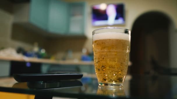 啤酒与电视遥控器 与电视运行在后台 — 图库视频影像
