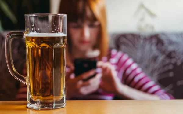 Flickan dricker öl och tittar in i telefonen — Stockfoto