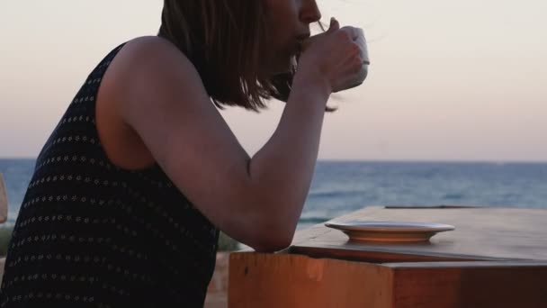 여자는 바다의 배경에 커피를 마십니다 — 비디오