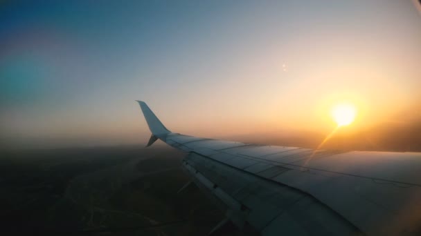 航空機の翼のフラップ 飛行機は飛んで ポートホールの夜明けを通して見える — ストック動画