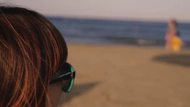 Uma Menina Óculos Sol Está Olhando Para Mar Silhuetas Pessoas — Vídeo de Stock