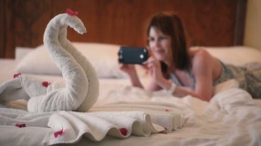 Kız telefonda havludan yapılmış bir kuğunun fotoğrafını çekiyor.