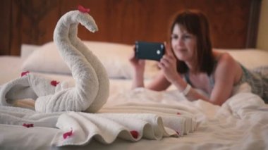 Kız telefonda havludan yapılmış bir kuğunun fotoğrafını çekiyor.