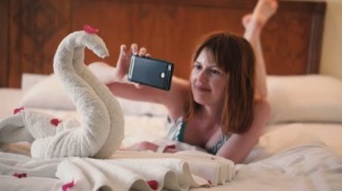 Kız telefonda havludan yapılmış bir kuğunun fotoğrafını çekiyor.