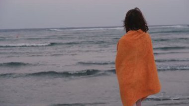 Havlu. Havluya sarılmış kız deniz kenarında duruyor