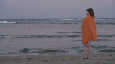 Havlu. Havluya sarılmış kız deniz kenarında duruyor