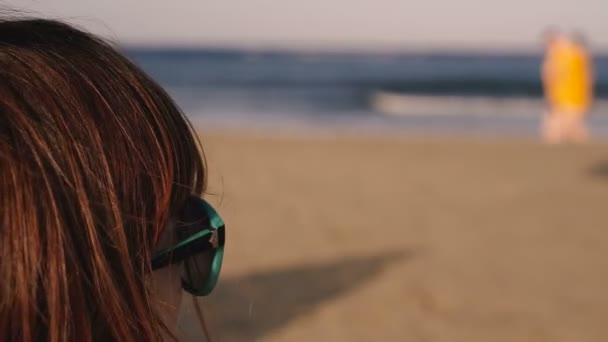 Güneş Gözlüklü Bir Kız Denize Bakıyor Insanların Siluetleri Kumsalda Yürüyor — Stok video