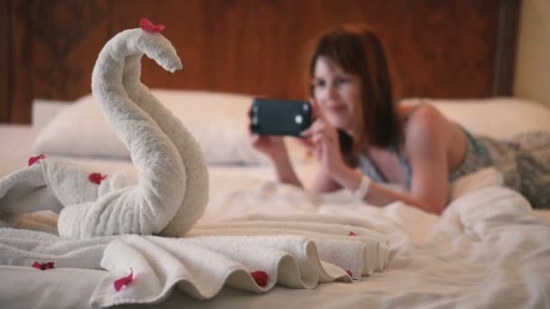 女孩在电话里拍一张用毛巾做的天鹅的照片 — 图库视频影像