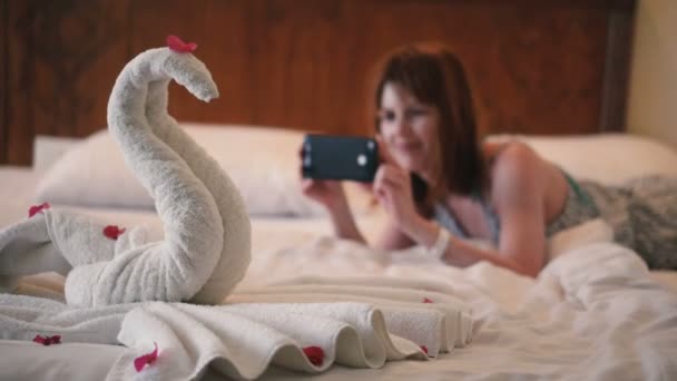 少女は電話でタオルで作られた白鳥の写真を撮る — ストック動画