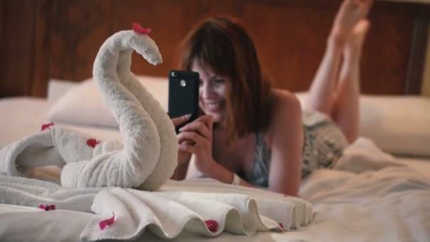 女孩在电话里拍一张用毛巾做的天鹅的照片 — 图库视频影像