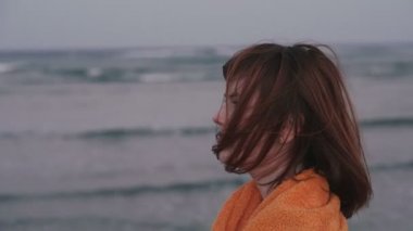 Havlu. Havluya sarılmış kız deniz kenarında duruyor