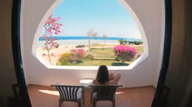 Denize bakan pencere. Kız loggiaya gider ve denize bakar.