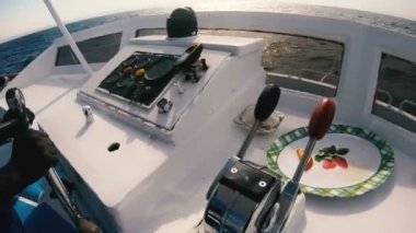Yat direksiyonu. Bronzlaşmış eller yatın direksiyonunu kontrol ediyor.