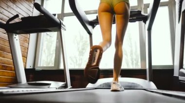 Koşu bandı. Kız spor salonunda bir koşu bandı üzerinde çalışır