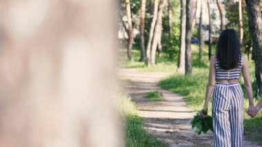 Büyükanne ve torunu el ele tutuşup parkta yürüyorlar.
