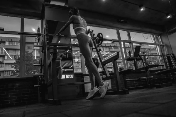 Barbell. Menina agachamentos com um sino — Fotografia de Stock